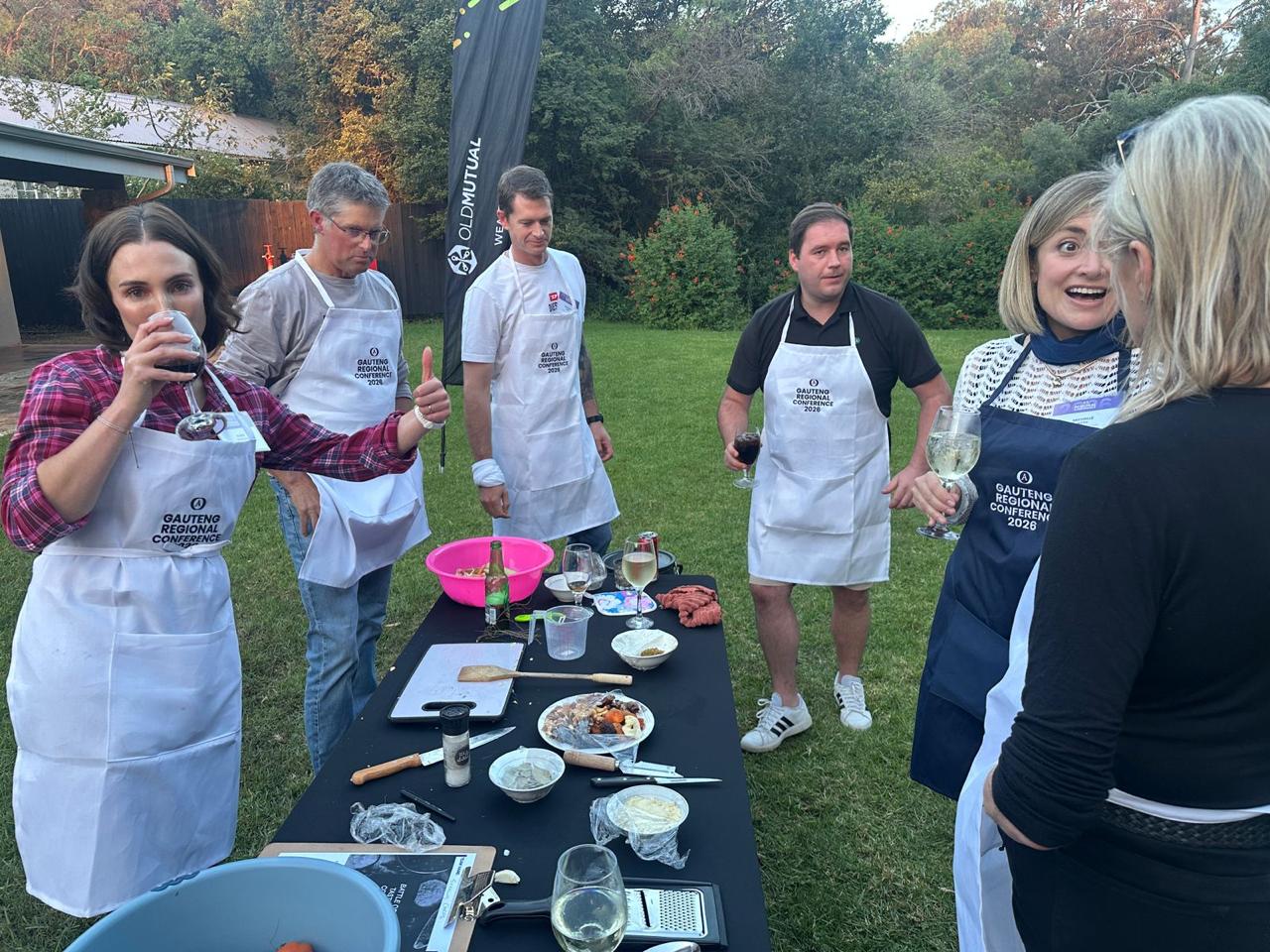Team in aprons cooking and laughing together at dusk