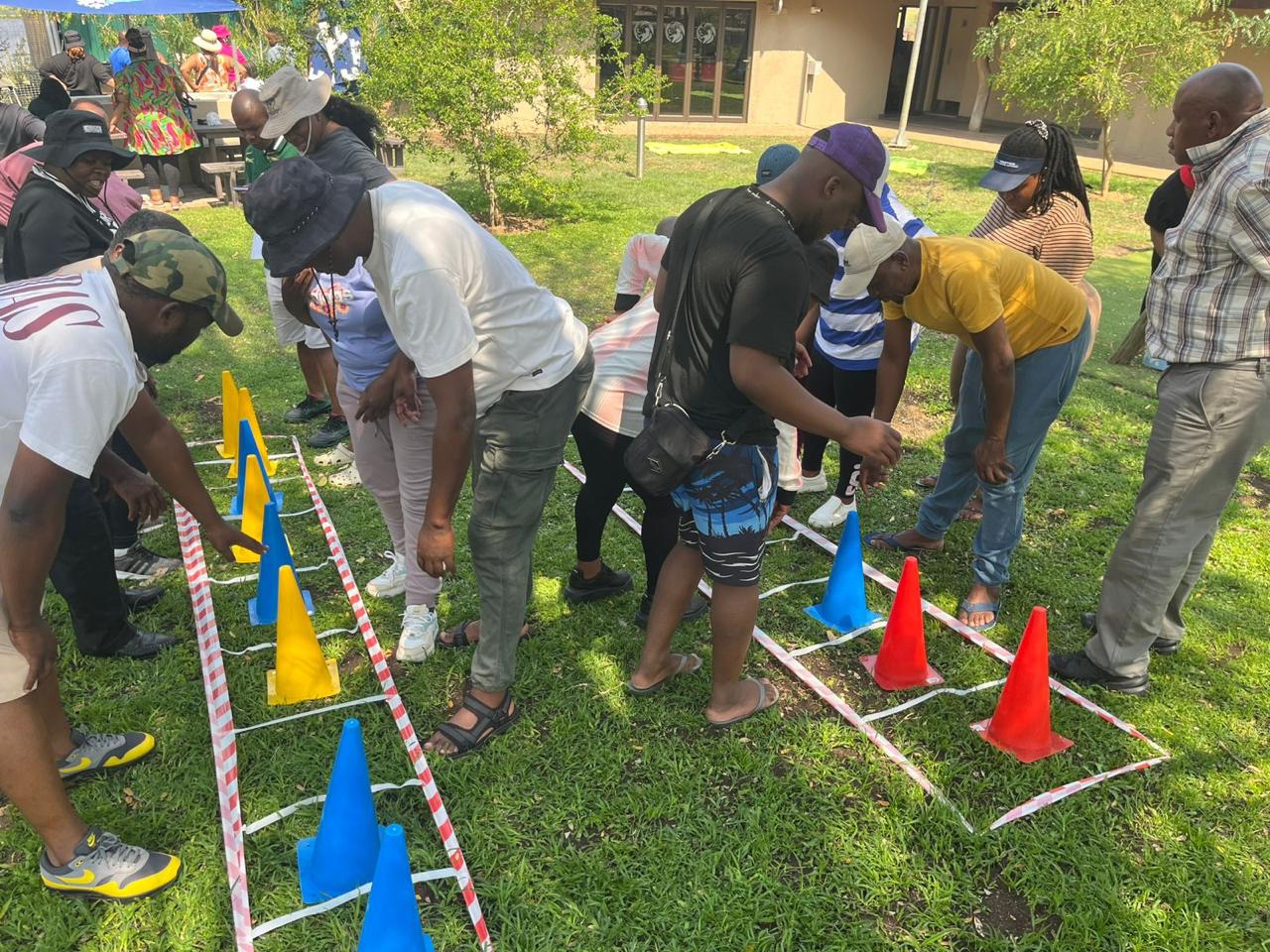Team working through a cone and tape obstacle course on a sunny lawn