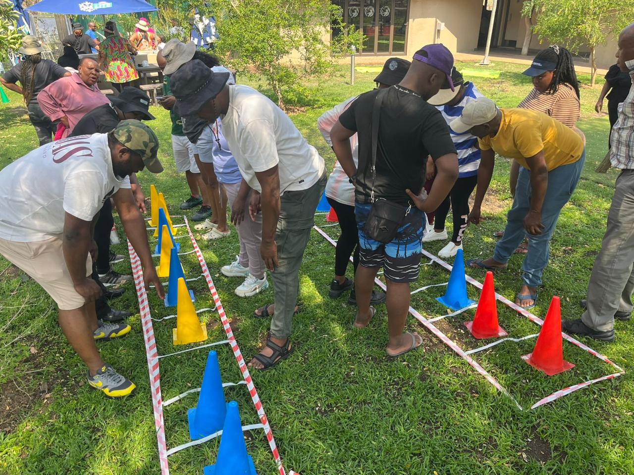 Team working through a cone and tape obstacle course on a sunny lawn