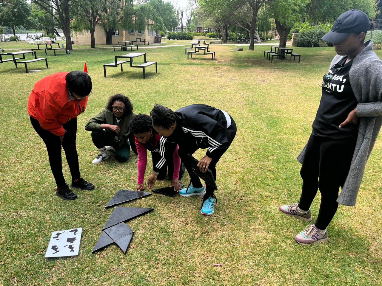 Team assembling a strategy puzzle together on the lawn