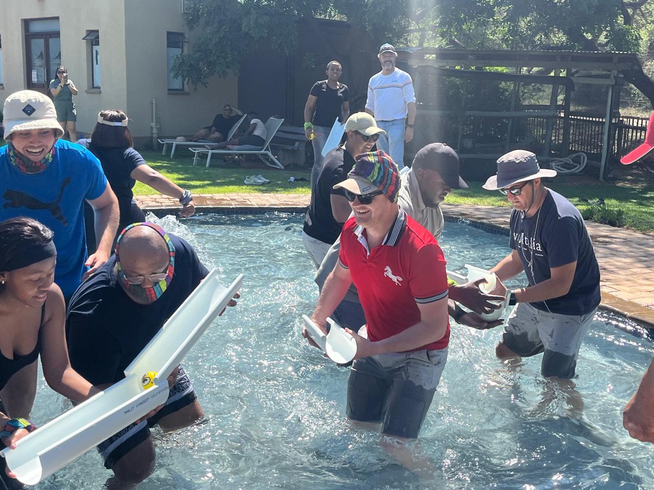 Team channeling water through gutters across a swimming pool