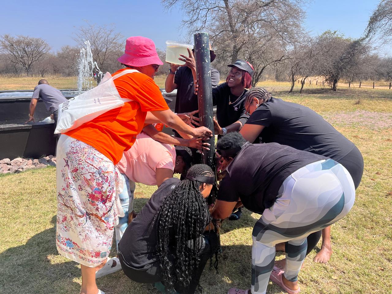 Team racing to fill a pole tube with water in the bushveld
